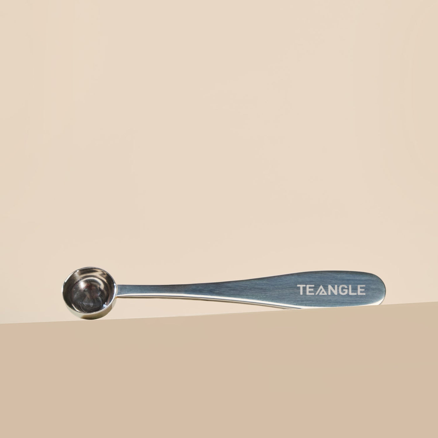 Matcha spoon with 'Teangle' branding on a beige background